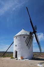 White windmill in a rural landscape under a blue sky on a sunny day with some clouds, Consuegra,