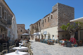 Picturesque alley with restaurant tables and traditional architecture under a blue sky, Old Town,