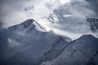 Dramatic mountain landscape, mountain valley, behind glaciated and snow-covered mountain peak Pik