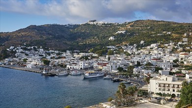 Panoramic view of a coastal town on a Greek island with white buildings and hills stretching to the