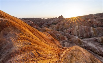 Erosion landscape of red and yellow sandstone, rock formations at sunrise with sun star, Skazka