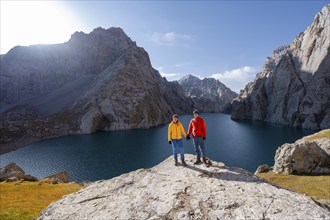 Couple at the blue mountain lake between rocky steep mountain peaks, Kol Suu Lake, Sary Beles