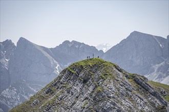 Mountaineer on a mountain peak with summit cross, summit of the Vorderunnütz, rocky peaks of the