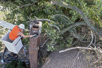 Detroit, Michigan, A worker dismantles a brick chimney after a storm with 70mph wind gusts blew