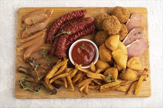 Set of snacks: sausages, fried potatoes, meat balls, dumplings, basturma on a cutting board on a