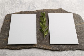 White paper business card, mockup with natural stone and boxwood branch on gray concrete background