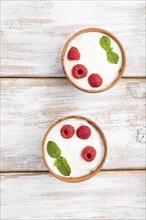 Yogurt with raspberry in clay cups on white wooden background. top view, flat lay, close up