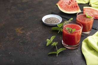 Watermelon juice with chia seeds and mint in glass on a black concrete background with green