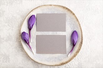 Gray paper invitation card, mockup with crocus flowers on ceramic plate and gray concrete