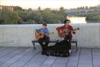 Two musicians playing guitar busking on Roman bridge, Cordoba, Spain, Europe