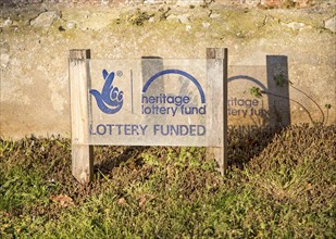 Sign in front of wall showing funding from Heritage National Lottery Fund, Suffolk, England, UK