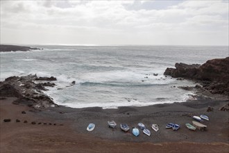 Fishing boats on the black beach of El Golfo, volcanic crater, cloudy sky, Lanzarote, Canary