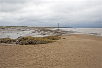 Muddy channel of the River Brue at low tide at its mouth at Burnham on Sea, Somerset, England,