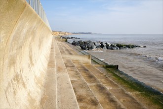 Curved wave return sea wall, steps and rock armour groynes, forming coastal defences at Southwold,