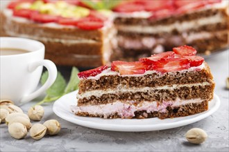 Homemade cake with yoghurt cream, strawberry, pistachio and a cup of coffee on a gray concrete