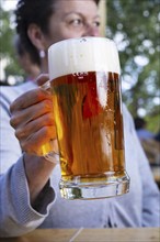 Woman (50-55) with a glass of beer in a beer garden, Prague, Bohemia, Czech Republic, Europe