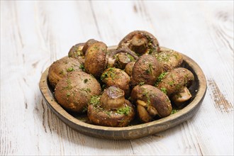 A variety of freshly picked mushrooms is beautifully arranged on a rustic wooden plate, sprinkled