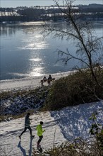 Winter in the Ruhr area, Lake Baldeney, snow-covered, partly frozen lake, walkers on the lakeside