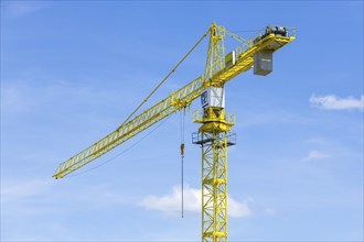 Construction crane in front of a blue sky, clouds