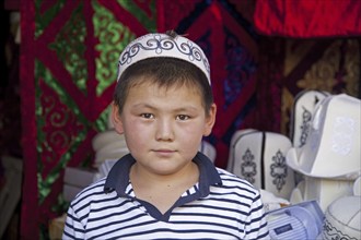 Kyrgyz boy wearing traditional tubeteika at market in Osh, Kyrgyzstan, Asia