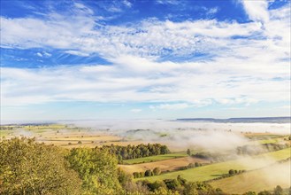 Scenics view of the countryside with fields and groves of trees and fog on a sunny autumn day