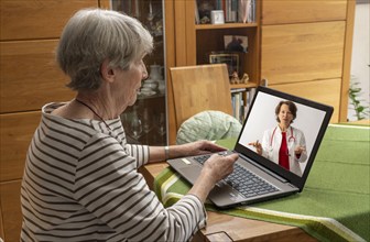 Symbolic image of telemedicine, patient speaking to a doctor in a video conference from home