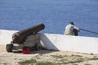 Cliff fishermen and historic cannon in the Fortaleza de Sagres, Vila do Infante, Sagres, Algarve,