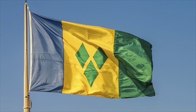 The flag of the Grenadines flutters in the wind, isolated against a blue sky