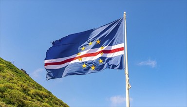 The flag of Cape Verde flutters in the wind, isolated against a blue sky