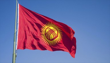 The flag of Kyrgyzstan, Kyrgyzstan, flutters in the wind, isolated against a blue sky, Asia