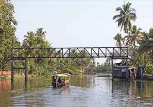 Traditional boat passes under a footbridge, canal system of the backwaters, Kerala, India, Asia