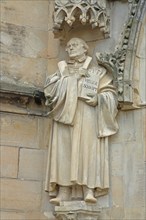 Sculpture and monument of Martin Luther with Bible, Holy Scripture, book at the portal of St