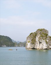 Tiny fishing boat and the huge karst rocks in Lan Ha Bay, Halong Bay, Vietnam, Asia