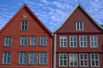 Traditional red wooden houses under a blue sky with pitched roofs and multiple windows in a sunny