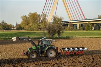 Farmer ploughing a field, tractor with plough, near Neuss, Fleher motorway bridge, A46, North