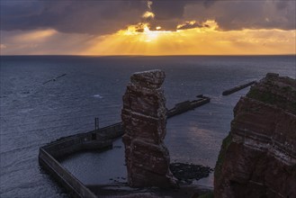 Red sandstone cliff with Lange Anna on the offshore island of Heligoland, mole as protection