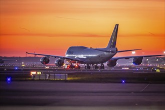 Early in the morning in front of sunrise at the airport, a jumbo jet stands ready for take-off on