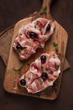 Breakfast, bacon and olives sandwich, on a cutting board, top view, close-up, no people