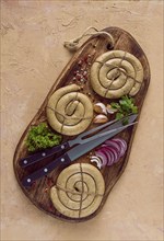 Raw spiral sausages, on a wooden board, top view, with spices, no people