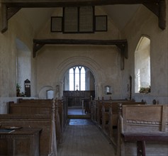 Norman chancel arch and wooden pews inside church of Saint John the Baptist, Wantisden, Suffolk,