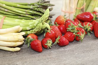 Green asparagus, white asparagus and fresh strawberries decorated on a rustic wooden table