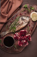 Fried dorado fish, with spices and herbs, on a wooden board, pomegranate sauce, close-up, no people