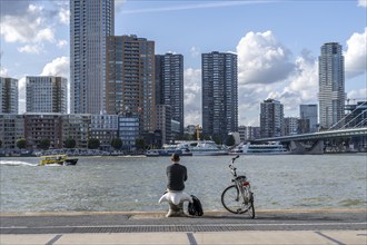 Skyline at the Nieuwe Maas, skyscrapers, man taking a break at the riverbank, Rotterdam,