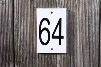 64, number, sixty-four, sign, The numbers 6 and 4 are written in black numbers on a white sign. The