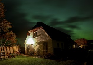 Northern Lights (Aurora borrealis) over a thatched roof house, Junkersmitteldeich, Pellworm Island,