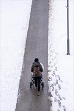 Winter in the city, cleared riverside path on the Main, woman with pram, Frankfurt, Hesse, Germany,