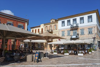 Lively street café with large parasols and colourful buildings under a blue sky, Syntagma Square,