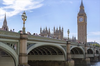 Tourists on a bridge in front of the famous landmark Big Ben under a blue sky, London, United