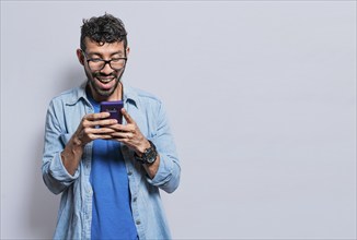 Smiling handsome boy texting with his cell phone isolated, young latin man happy with his cell