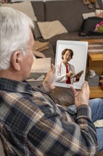 Symbolic image of telemedicine, patient speaking to a doctor in a video conference from home